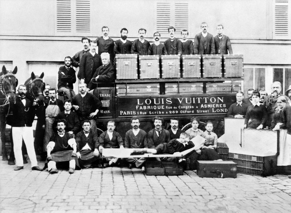1888 年,Asnières 工坊门前。车厢上写着 Fabrique 和 Asnières,车顶那排就是当时的平顶旅行箱——边角包铜、木条加固,能一只叠一只